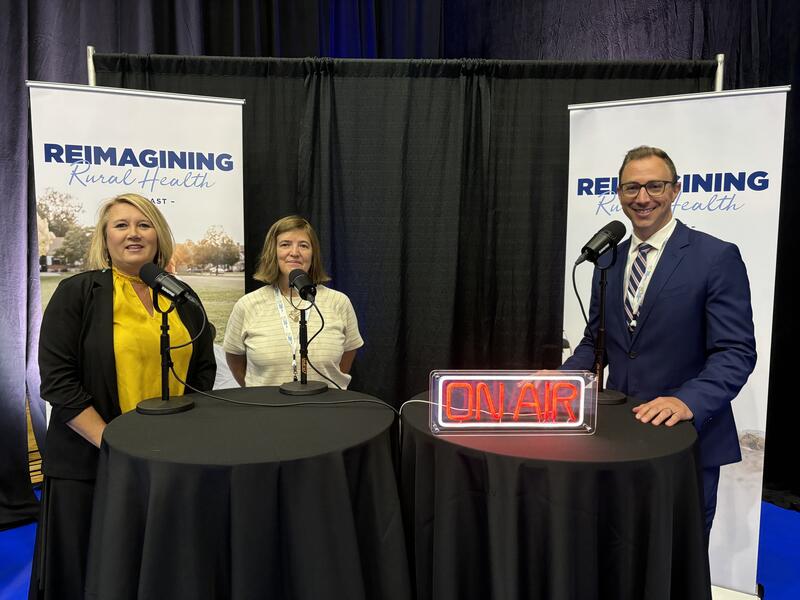 two ladies are standing by microphone on the left and a mane is by a microphone on the right side