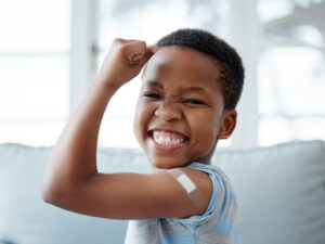 Portrait of a little boy with a plastic bandage on his arm after an immunization.