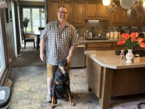 A man and his dog pose for a photo in the kitchen.