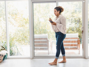 A mid adult woman walks around her living room barefoot as she chats on her smart phone with her doctor.