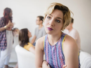 Portrait of woman sulking at party, turned away from friends.