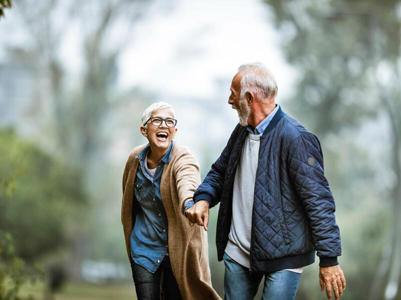 Cheerful senior couple having fun in the park. Focus is on woman. Copy space.