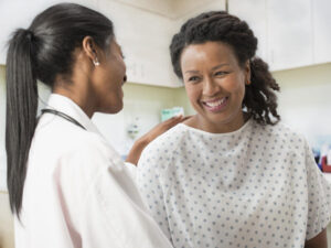 Doctor comforting patient in hospital gown.