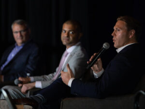 Three businessmen speak on stage at the Summit on the Future of Rural Health Care.