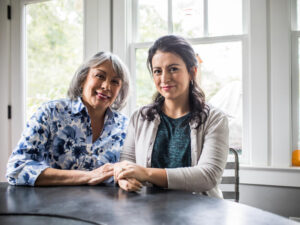 Portrait of senior woman and adult daughter in kitchen.