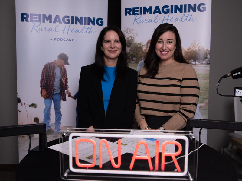 two women standing together behind lit on-air sign