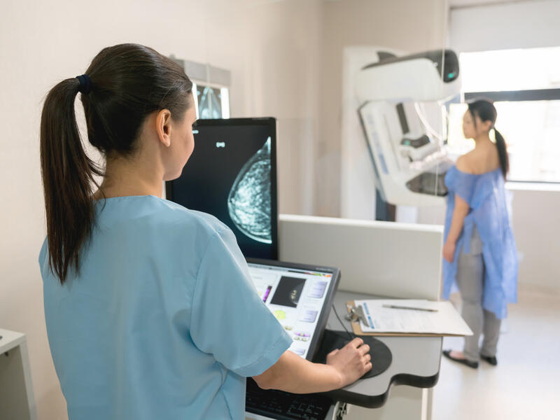 Unrecognizable nurse taking a mammogram exam to an adult patient at the hospital