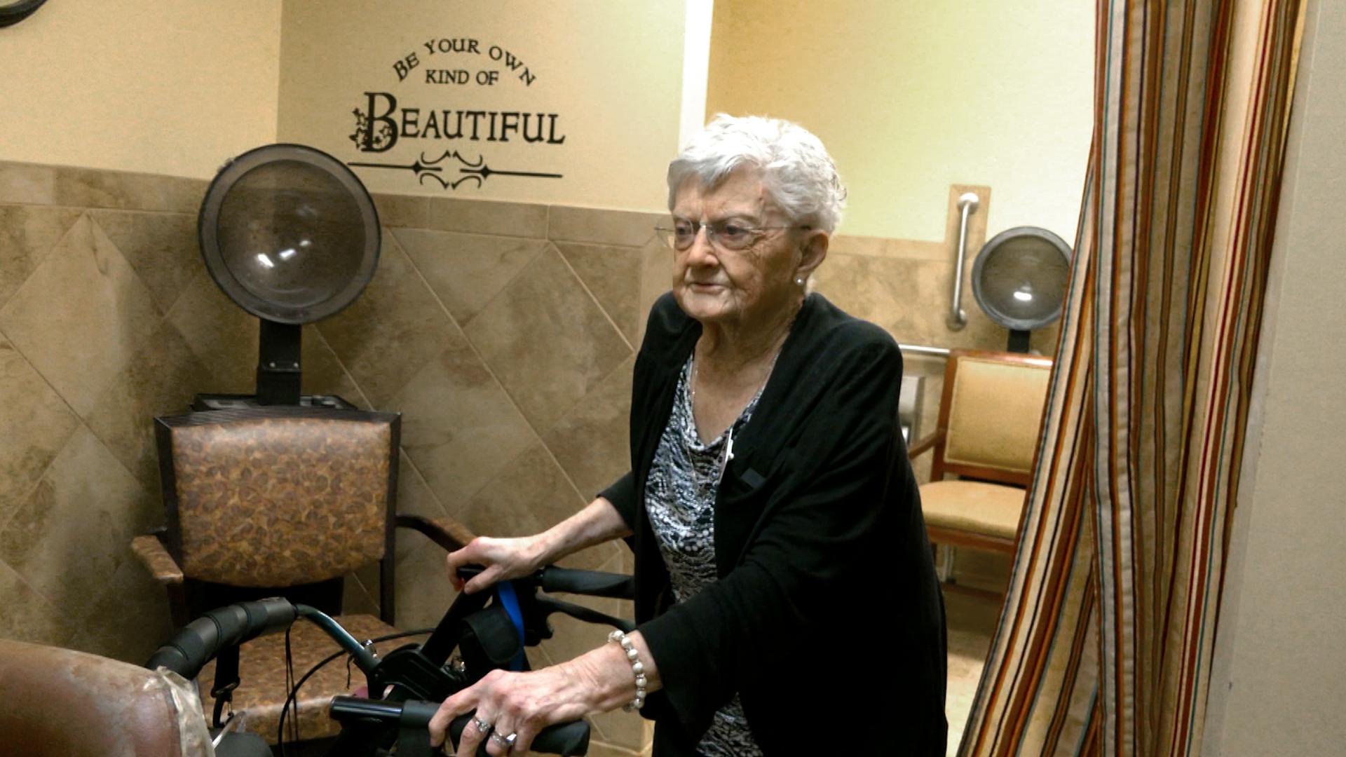 Senior woman with walker enters hair salon.