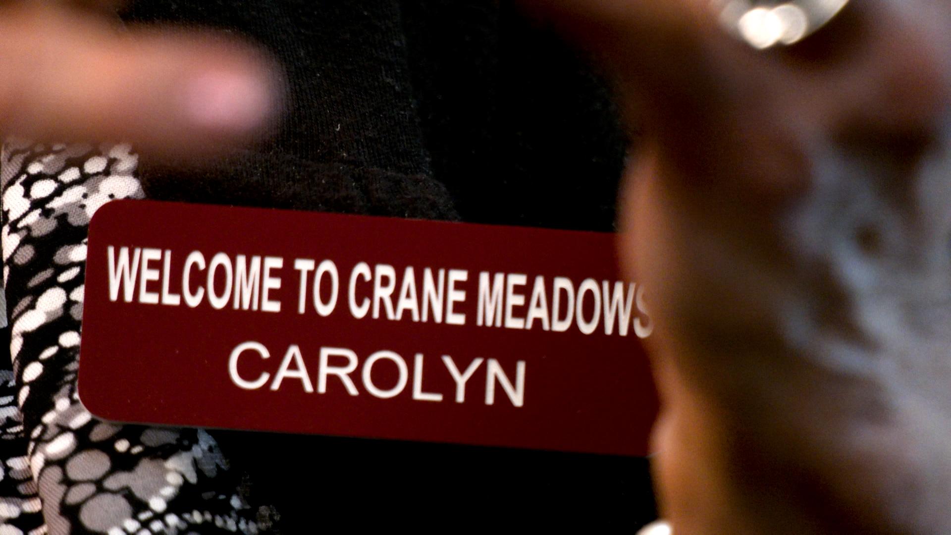 Closeup of red and white nametag: "Welcome to Crane Meadows. CAROLYN"