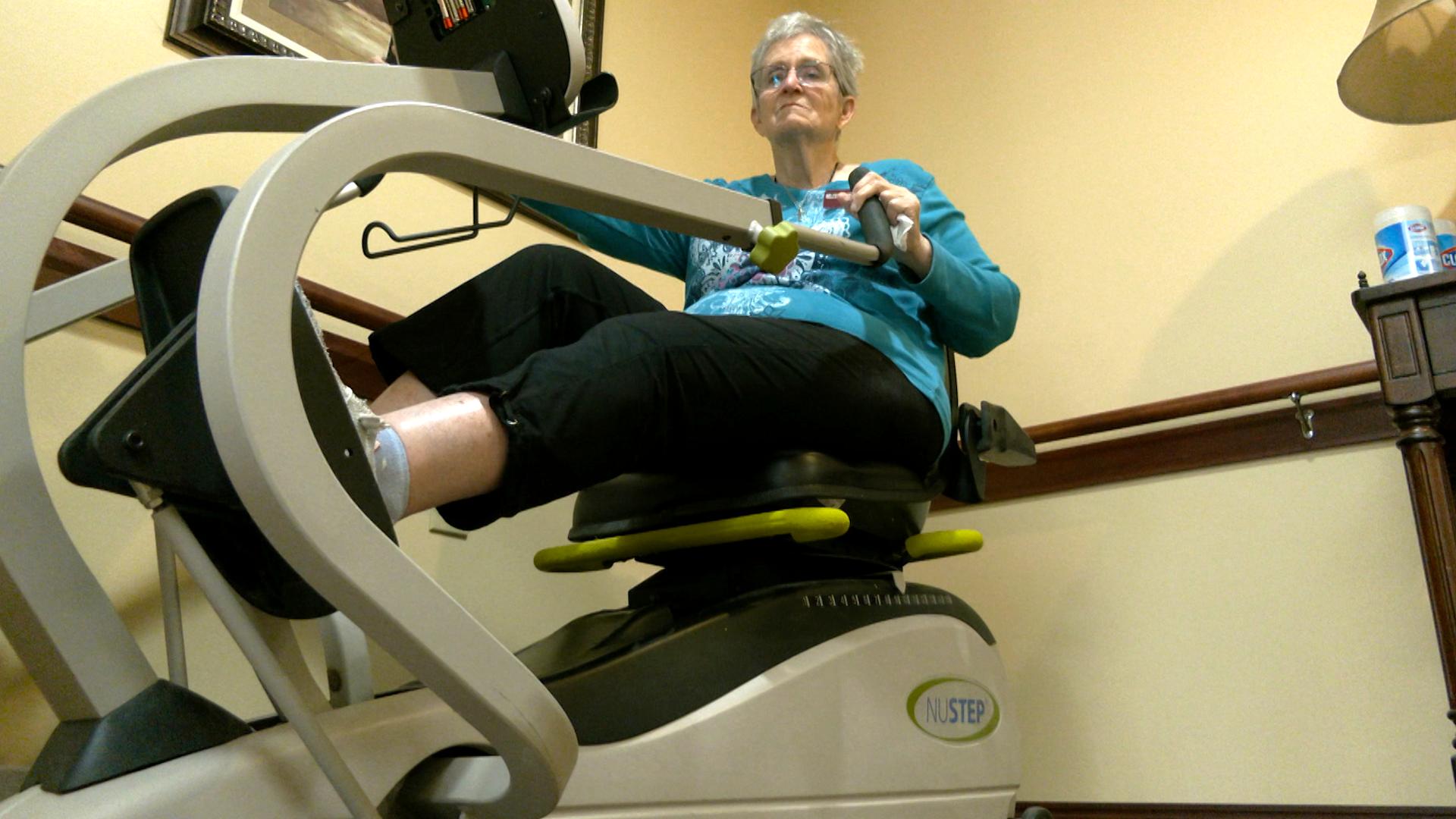 Senior woman rides a stationary bike.
