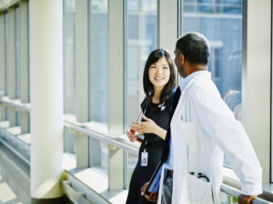 Smiling doctors in discussion in hospital corridor.