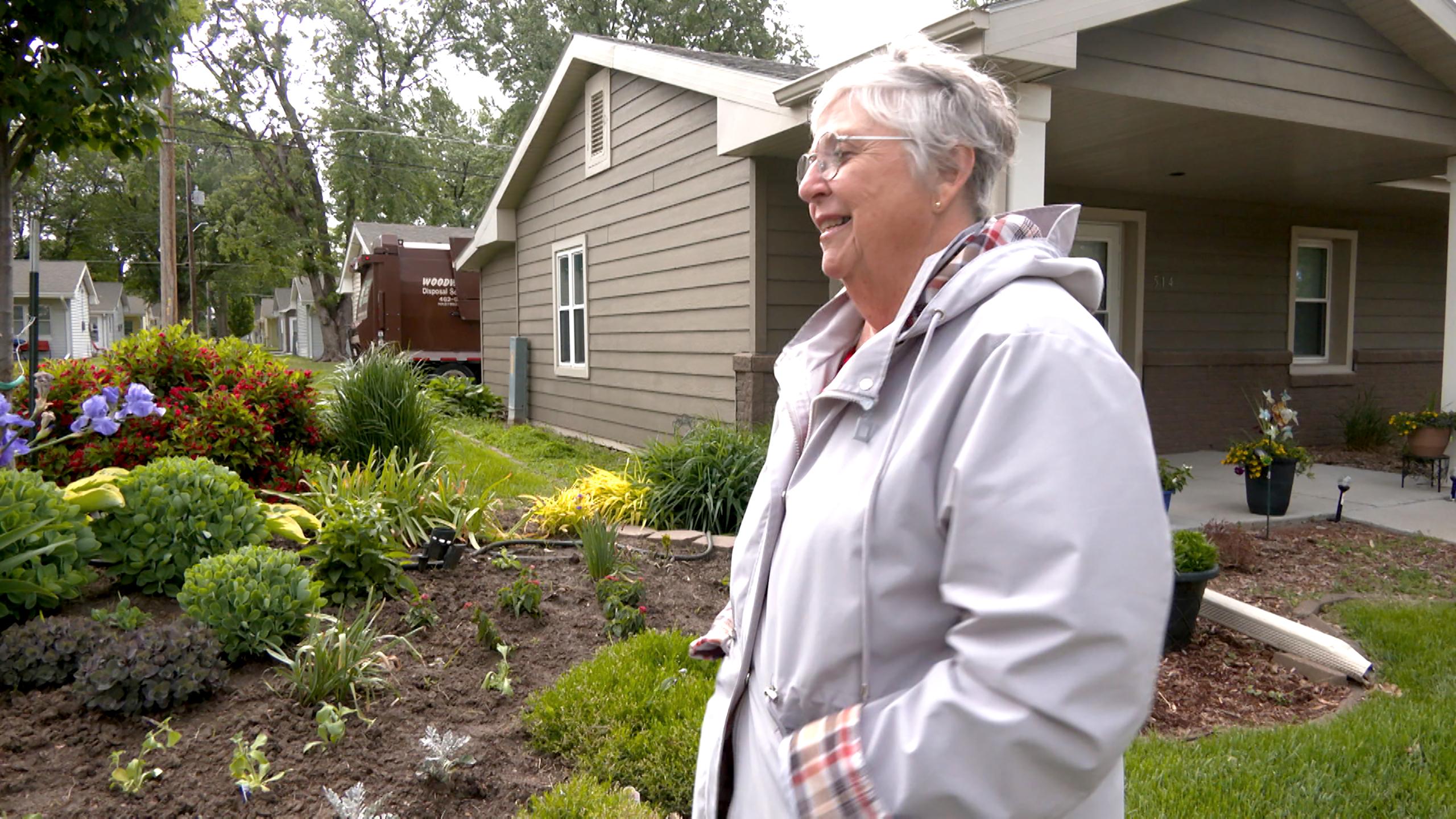Senior woman outside looks left to her spring garden.