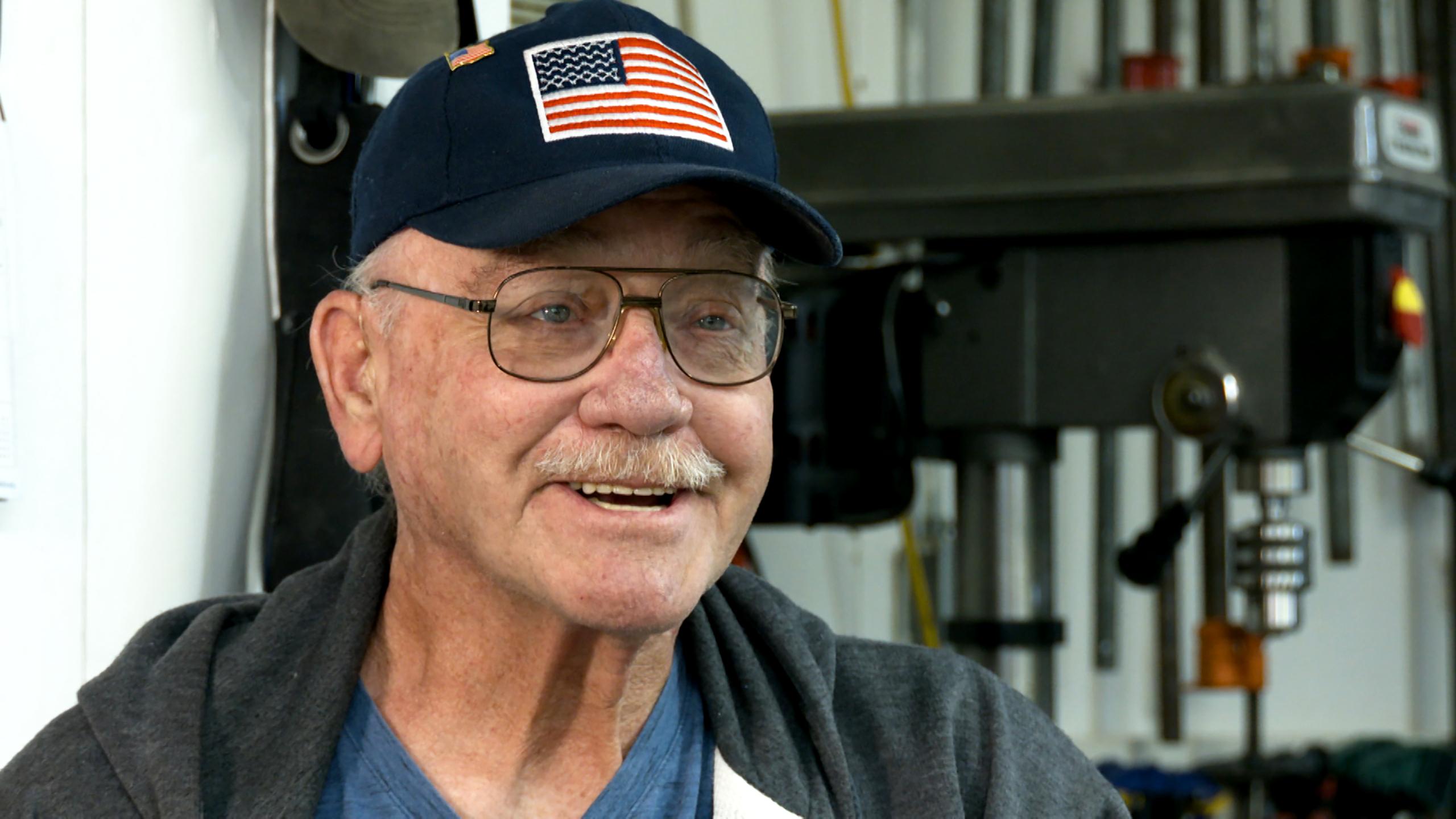 Happy senior man in a baseball cap decorated with an American flag.