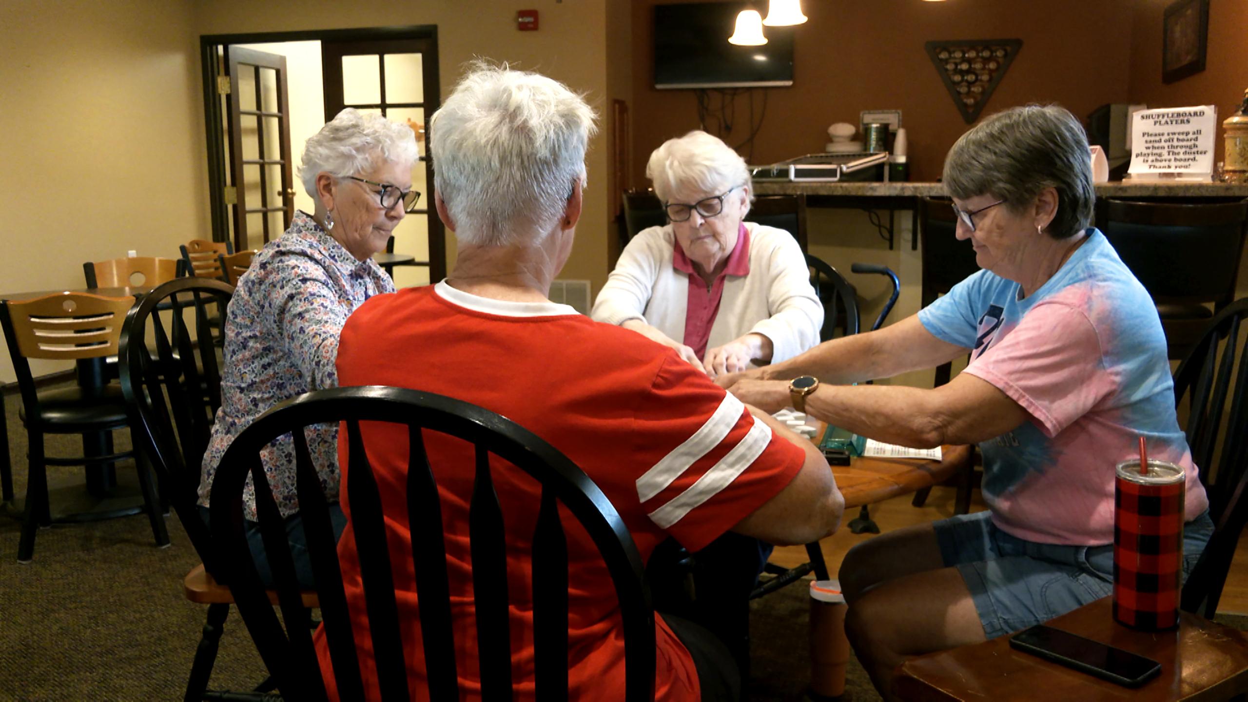 Senior women playing mahjong around a table.