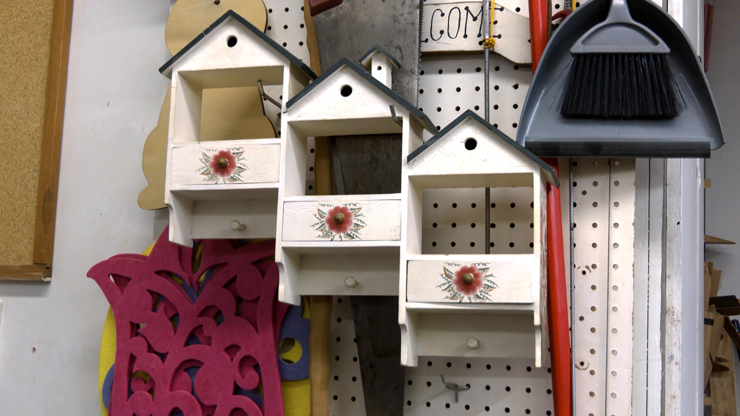 Three wooden birdhouses hang on the wall of a shop.