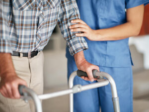 Nurse helping senior patient who's using a walker for support.