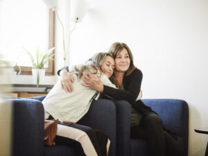 Mother and daughter embracing while sitting at wellness center.