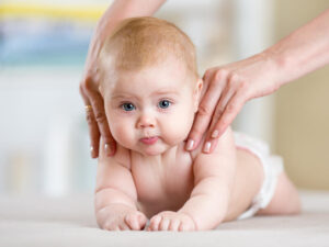 Mother giving massage to her baby at home.