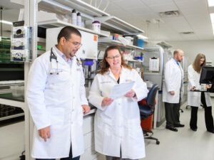 Pharmacists in lab coats review PGx test results on paper.
