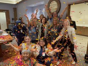 Group of excited nurses throwing orange and yellow confetti.