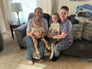 Two boys snuggle with their two moms at home.