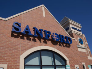 Looking up at a brick Sanford Health clinic sign and tower.