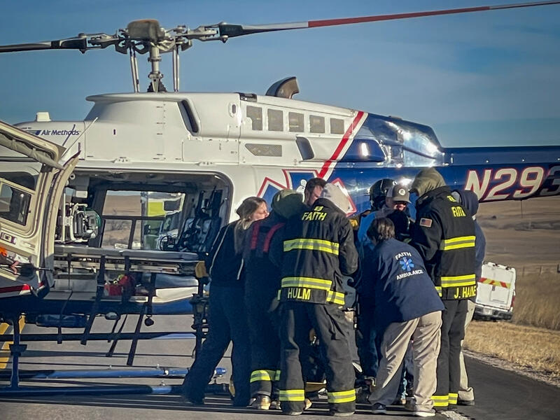 Firefighters and paramedics prepare to load a patient onto a helicopter.