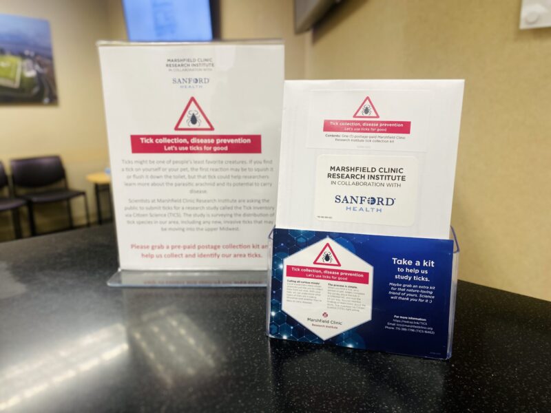 Two flyers standing on a countertop promote "Tick collection, disease prevention," a study by Marshfield Clinic Research Institute in collaboration with Sanford Health.