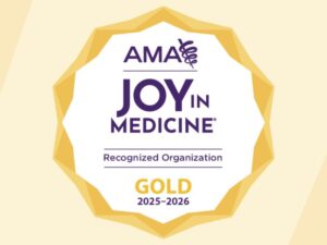 Yellow wreath around purple words: "AMA Joy in Medicine gold recognized organization 2025-2026."