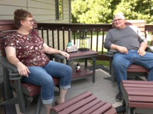 A mature couple looks content in their back porch chairs.