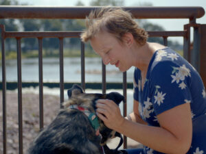 Young woman pets her dog on a sunny day in the city.