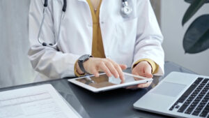 A physician's hands using a tablet computer.