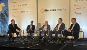 Five businessmen sit on stage with Reuters Events backdrop.