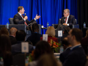 Two businessmen sit on stage during the rural health care summit.