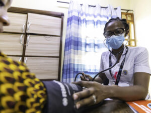 Nurse midwife measures a patient's blood pressure in an exam room in Ghana, West Africa.