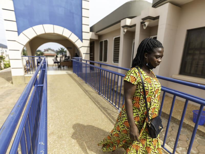 A woman walks down a ramp from an arched entryway to a clinic in Ghana, West Africa.