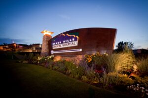Sign in prairie flowerbed, lit at dusk, says "Black Hills Surgical Hospital."