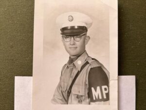 Black and white photo on a table shows a young man with an "MP" armband on his military police uniform.