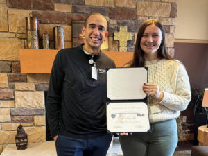 Two people hold a folder with an award certificate.