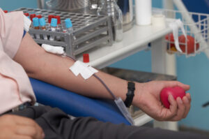 A man's arm hooked up to blood donation tubes and bandages.