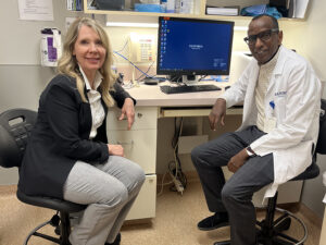 Patient and doctor smile at a desk in an exam room.