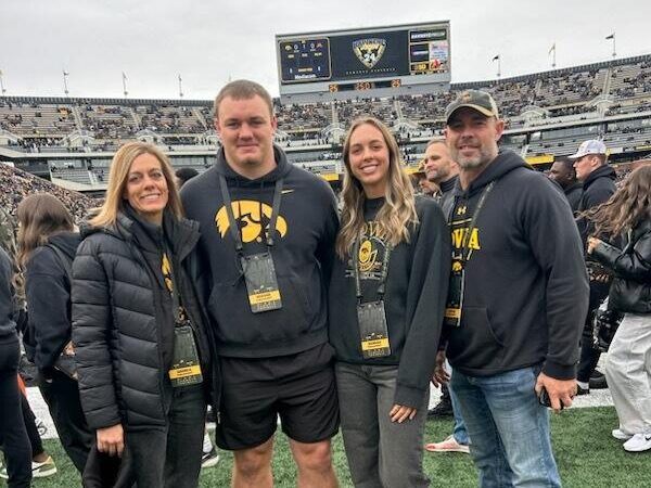 mom, teenage son and daughter, dad, standing on the field of a football stadium.