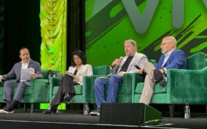 Screenshot of four businesspeople sitting on stage