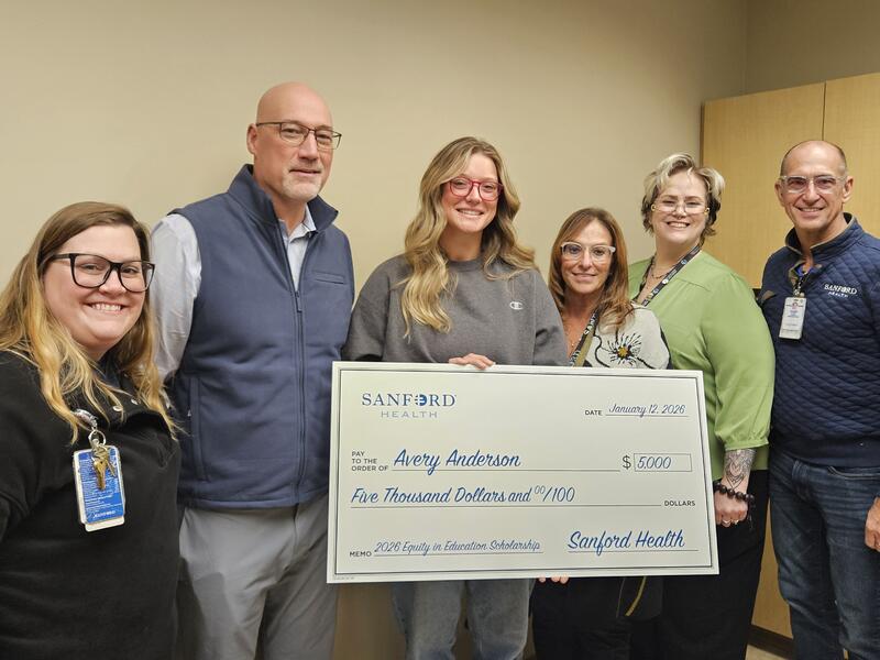 Five people pose with a giant check made out to Avery Anderson for Sanford Health Equity in Education Scholarship.