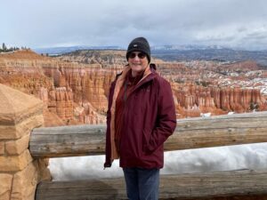 Mature woman stands at the edge of the Grand Canyon in winter.