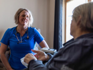 Home health nurse sits with a senior client.