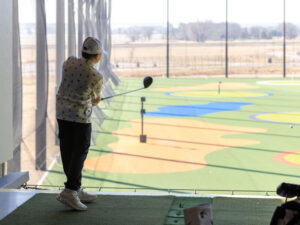 10-year-old golfer finishes his swing over a range below.