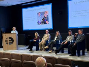 Businesspeople on a stage give a presentation.