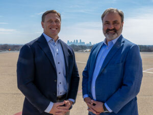 Two businessmen with the Minneapolis skyline between them.
