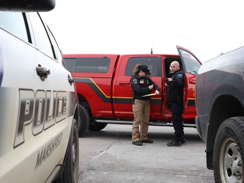 Police officers talk between police and fire vehicles.